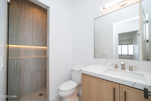 bathroom featuring a tile shower, toilet, and vanity