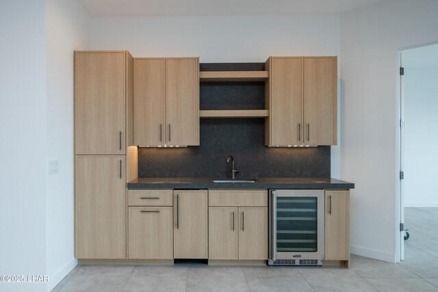 bar featuring decorative backsplash, beverage cooler, baseboards, and a sink