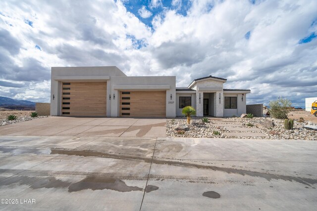 modern home featuring stucco siding, an attached garage, and driveway