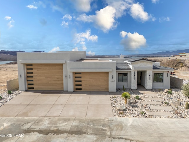 contemporary home featuring stucco siding, a mountain view, concrete driveway, and a garage