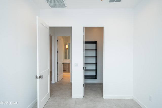 unfurnished bedroom with visible vents, baseboards, and a walk in closet