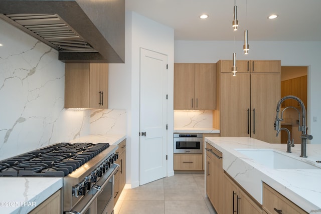 kitchen featuring light stone counters, exhaust hood, light brown cabinets, and appliances with stainless steel finishes