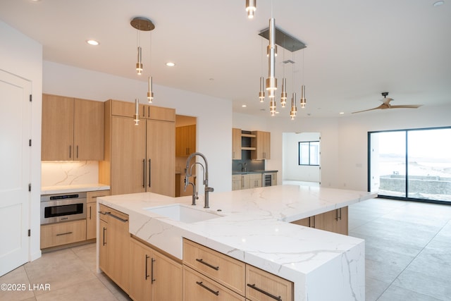 kitchen featuring a sink, oven, and light brown cabinetry