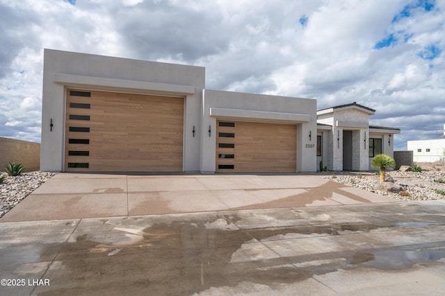 contemporary house featuring stucco siding, concrete driveway, and an attached garage