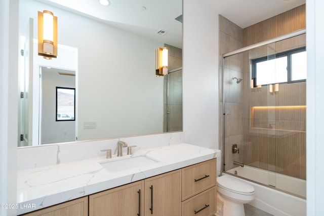 bathroom featuring vanity, toilet, visible vents, and combined bath / shower with glass door