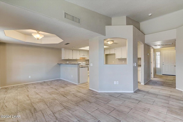 kitchen featuring white electric stove, kitchen peninsula, a raised ceiling, and white cabinets