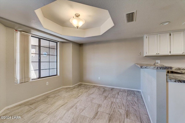 spare room featuring a tray ceiling and a textured ceiling