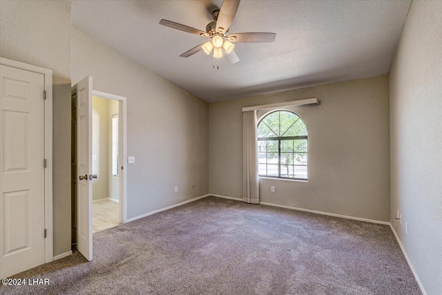 unfurnished room featuring ceiling fan, light colored carpet, and a textured ceiling