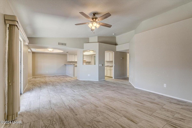 unfurnished living room featuring a textured ceiling, vaulted ceiling, and ceiling fan