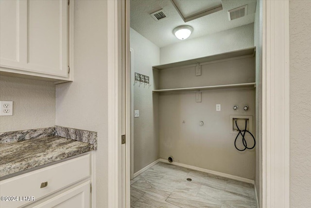 washroom featuring cabinets, washer hookup, a textured ceiling, and hookup for a gas dryer