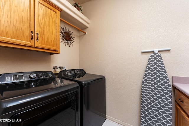 laundry room with cabinet space, a textured wall, and washing machine and clothes dryer