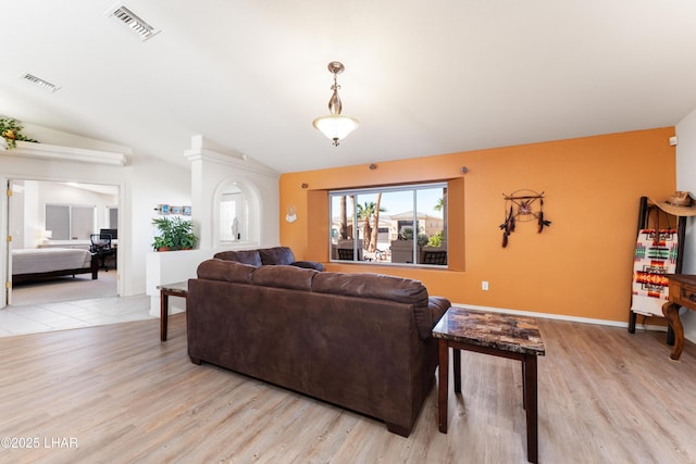 living area with light wood finished floors, baseboards, visible vents, and vaulted ceiling