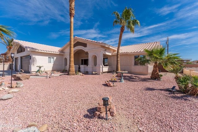 view of front of house featuring a garage, a tiled roof, and stucco siding