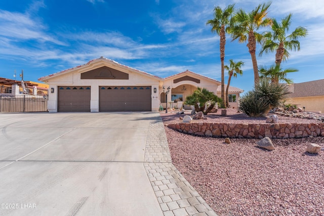 ranch-style house featuring a garage, stucco siding, driveway, and fence