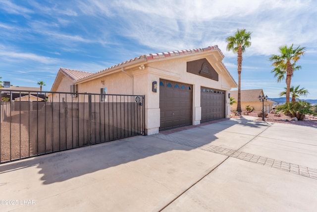 view of home's exterior with a gate, driveway, fence, and stucco siding