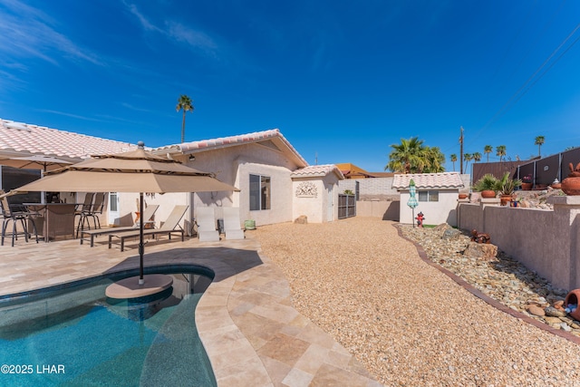 back of house featuring a fenced in pool, a fenced backyard, a tiled roof, a patio area, and stucco siding