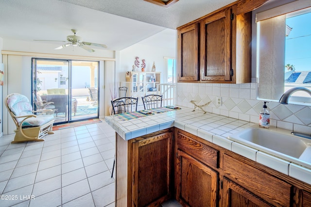 kitchen featuring sink, tile counters, backsplash, and light tile patterned floors