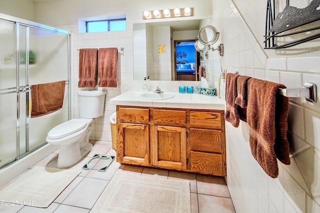 bathroom with tile walls, vanity, a shower with shower door, and tile patterned floors