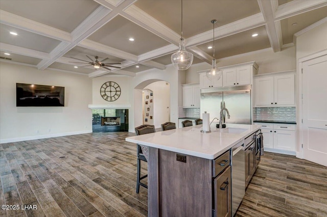 kitchen with stainless steel appliances, dark wood-style floors, arched walkways, a sink, and a ceiling fan