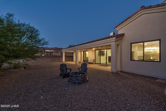 back of property featuring a fire pit, a tile roof, a patio, and stucco siding