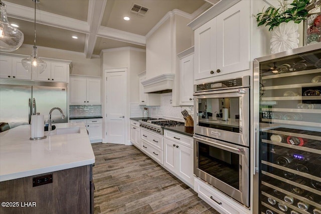kitchen featuring coffered ceiling, visible vents, ornamental molding, a sink, and appliances with stainless steel finishes