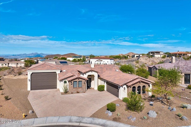 mediterranean / spanish-style house featuring stucco siding, an attached garage, and a tile roof