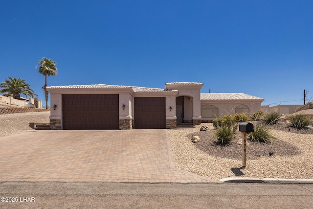 679 Apache Dr, Lake Havasu City, AZ 86406 - view of front of property with an attached garage, stucco siding, decorative driveway, a tiled roof, and stone siding