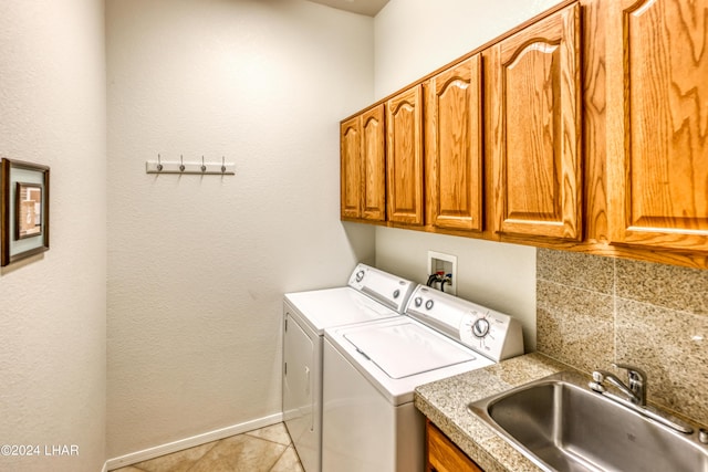 laundry area featuring sink, light tile patterned floors, washing machine and dryer, and cabinets