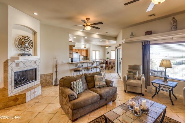 tiled living room featuring a tile fireplace and ceiling fan