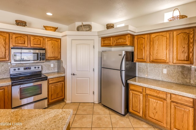 kitchen with stainless steel appliances, decorative backsplash, and light tile patterned floors