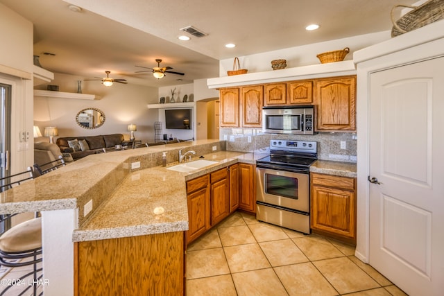 kitchen with sink, a breakfast bar, backsplash, stainless steel appliances, and kitchen peninsula