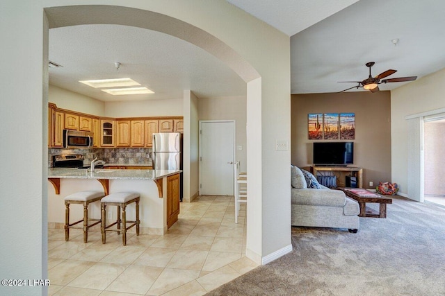 1650 Smoketree Ave Unit 202, Lake Havasu City, AZ 86403 - kitchen featuring stainless steel appliances, a kitchen breakfast bar, light stone counters, tasteful backsplash, and light colored carpet