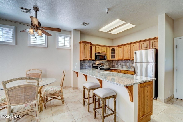 1650 Smoketree Ave Unit 202, Lake Havasu City, AZ 86403 - kitchen featuring sink, a breakfast bar area, stainless steel appliances, light stone countertops, and decorative backsplash