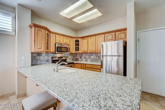 1650 Smoketree Ave Unit 202, Lake Havasu City, AZ 86403 - kitchen featuring appliances with stainless steel finishes, sink, a breakfast bar area, decorative backsplash, and kitchen peninsula