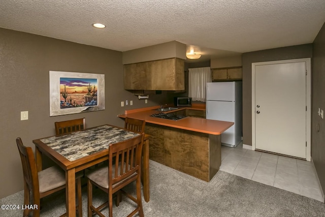 kitchen featuring sink, light carpet, white fridge, and a textured ceiling