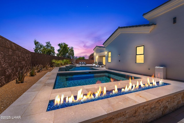 816 Isola Bella Loop, Lake Havasu City, AZ 86403 - pool at dusk with an outdoor fire pit, a fenced backyard, a patio, and a pool with connected hot tub