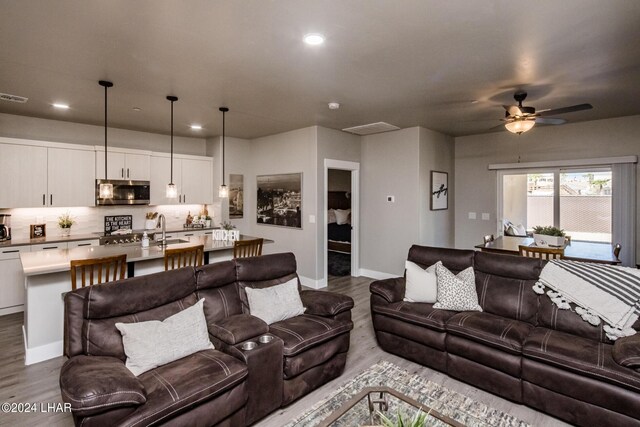 living room with hardwood / wood-style flooring, sink, and ceiling fan