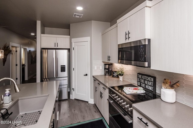 kitchen with tasteful backsplash, appliances with stainless steel finishes, sink, and white cabinets