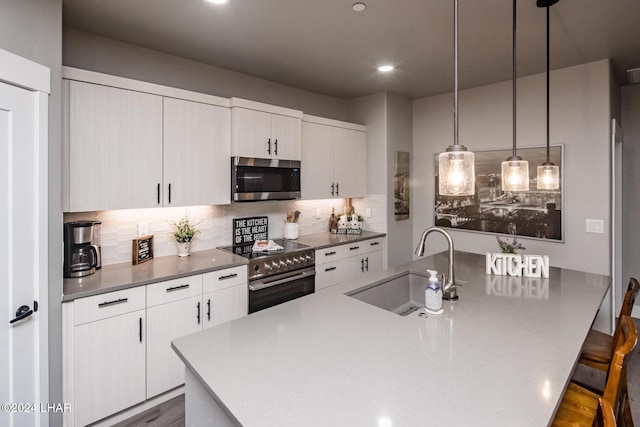 kitchen featuring appliances with stainless steel finishes, sink, backsplash, a kitchen bar, and hanging light fixtures