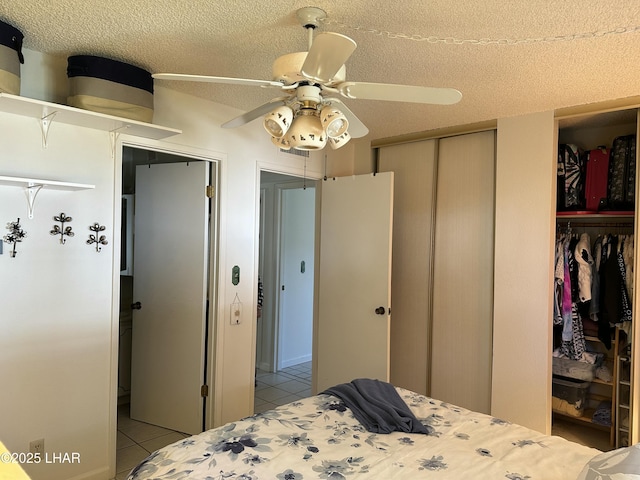 bedroom with a textured ceiling, light tile patterned flooring, and ceiling fan