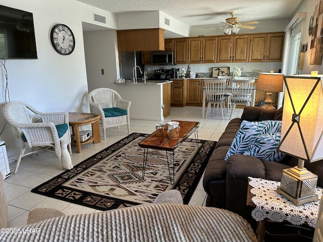 living room with light tile patterned floors, ceiling fan, a textured ceiling, and sink