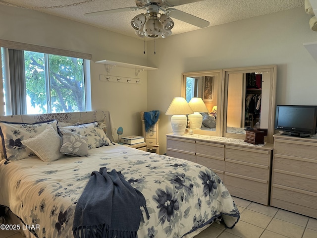 tiled bedroom with a textured ceiling and ceiling fan