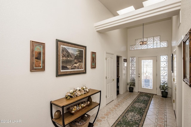 tiled foyer entrance featuring a high ceiling and a skylight