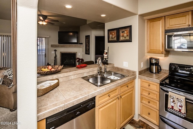 kitchen with sink, tile counters, light brown cabinets, and appliances with stainless steel finishes