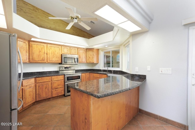 2624 Rainbow Ave N, Lake Havasu City, AZ 86403 - kitchen featuring a peninsula, dark stone counters, a sink, ceiling fan, and stainless steel appliances