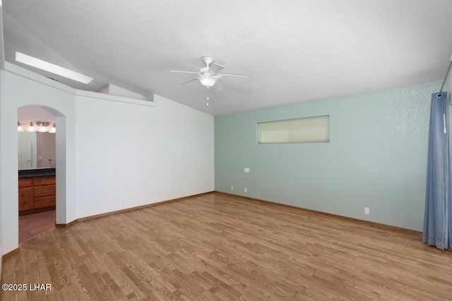 2624 Rainbow Ave N, Lake Havasu City, AZ 86403 - empty room with light wood finished floors, vaulted ceiling, arched walkways, a textured ceiling, and a ceiling fan