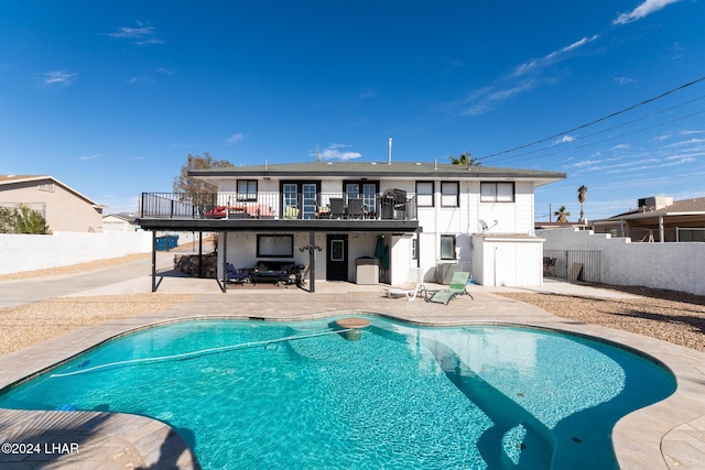 back of house featuring a fenced in pool, a fenced backyard, a patio, and a balcony