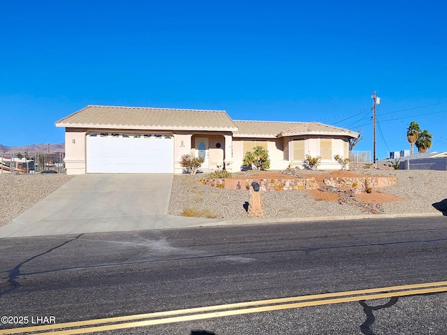 ranch-style house with an attached garage, a tile roof, concrete driveway, and stucco siding