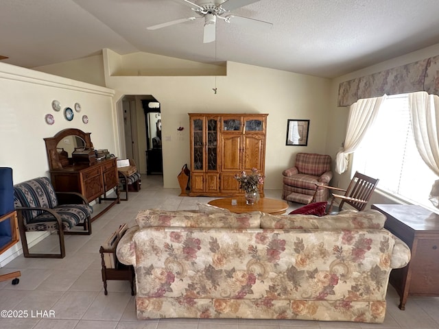 living room featuring lofted ceiling, a textured ceiling, light tile patterned flooring, and a ceiling fan