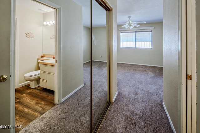 8731 Yaqui, Parker, AZ 85344 - hallway featuring baseboards, dark wood-style flooring, a textured wall, and dark colored carpet